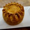 Whole pork pie on a white plate